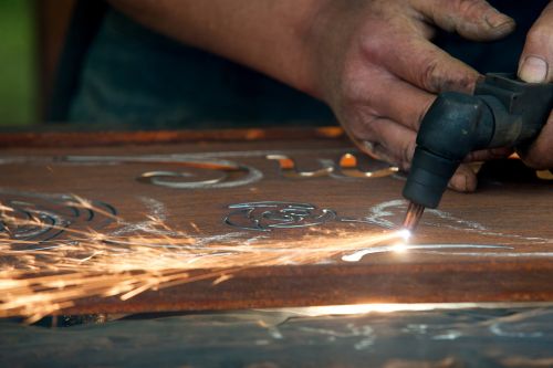 Mann schneidet per Hand Musterungen in Metall