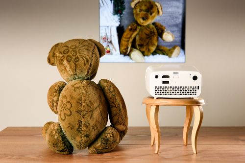 Teddybär sitzt neben Mini-Beamer