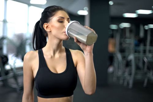 Frau trinkt proteinshake im fitnessstudio