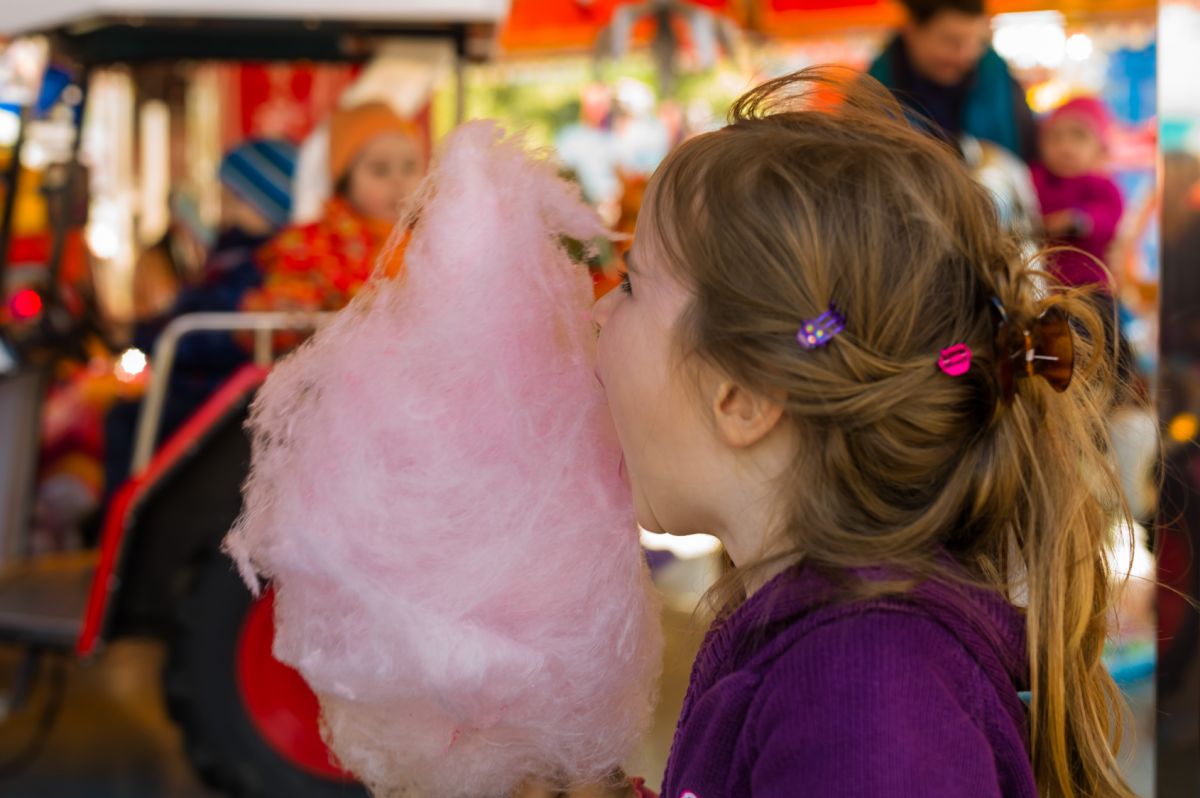 zuckerwattemaschine-kind isst zuckerwatte auf jahrmarkt